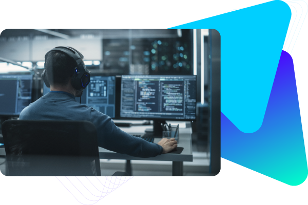 Person working at a computer station with multiple monitors displaying data and charts.