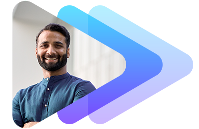 A smiling man in a blue shirt with arms crossed, standing outdoors with a blurred background.