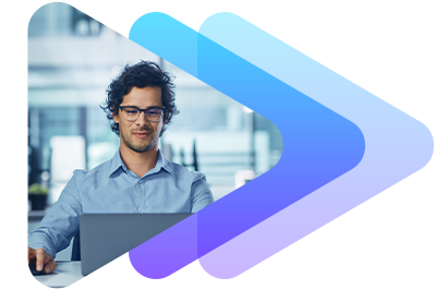 A man with curly hair and glasses working on a laptop outdoors.