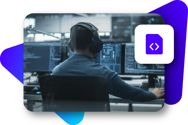 A person wearing headphones working at a computer in a dimly lit control room.