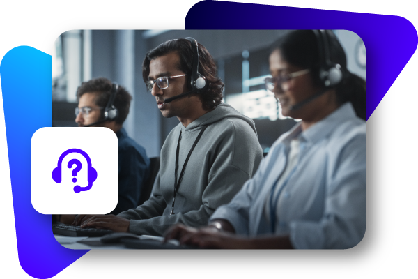 Three people wearing headphones and glasses sit side by side at computers in a dimly lit, modern office.