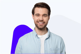 A smiling man with dark hair and a beard, wearing a light blue shirt, against a light background.