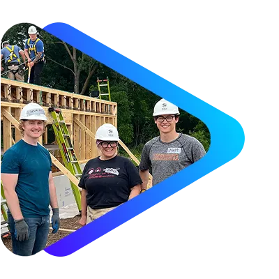Three Perforce employees wearing hard hats and gloves stand outdoors in front of a construction site.