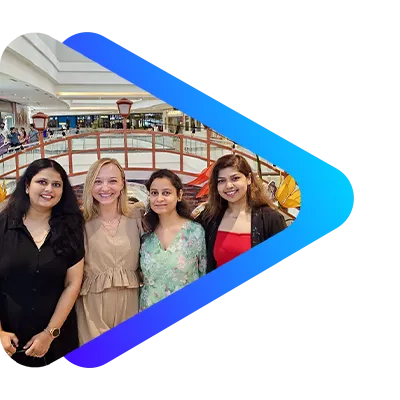 Four women standing together in an indoor shopping mall, smiling.